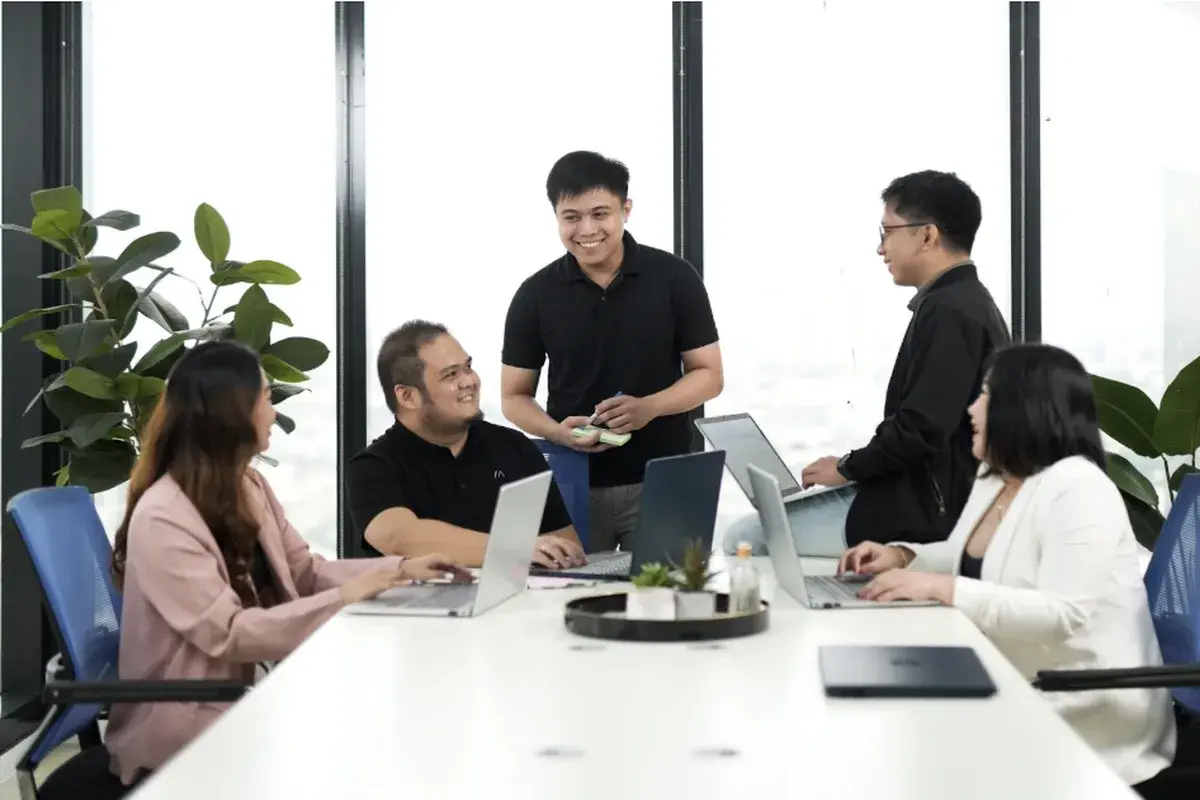 Team of professionals collaborating in a modern office meeting with laptops and discussion around a conference table