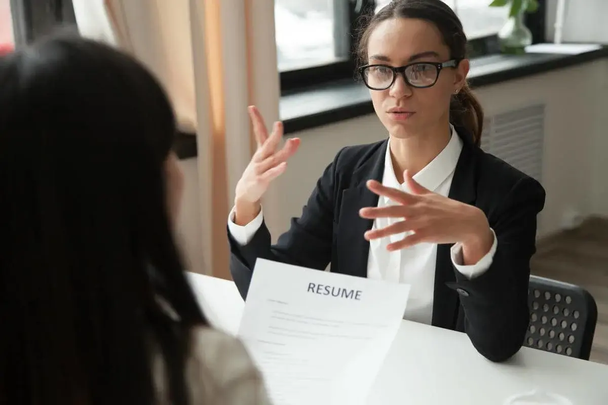 Confident female job applicant with glasses discussing her resume during a professional interview meeting