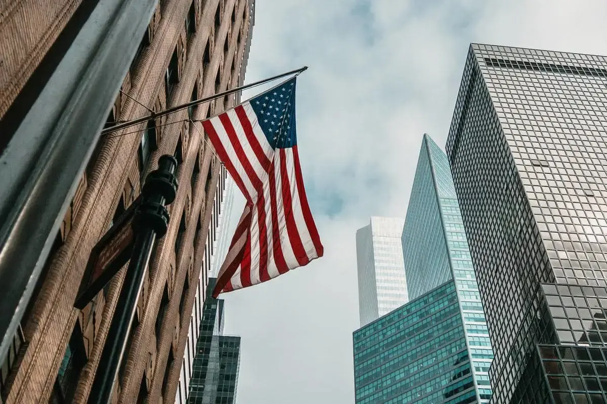 American flag on a city building with modern skyscrapers and cloudy sky in urban USA business district